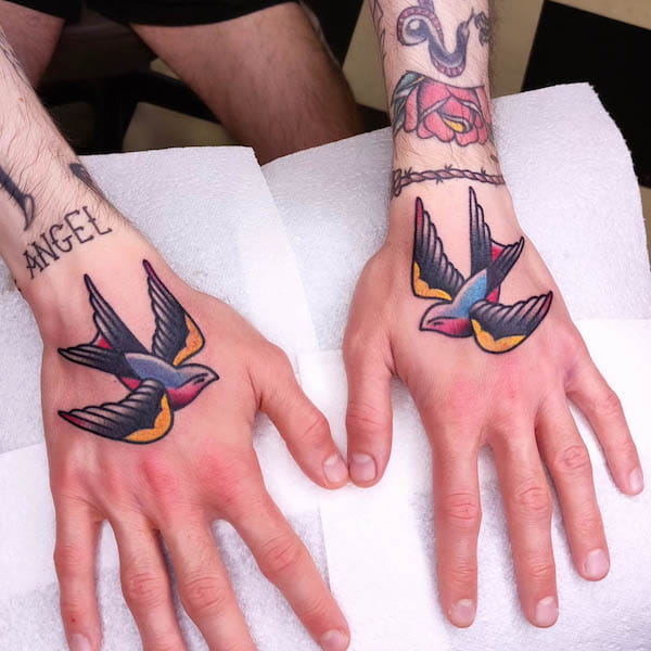 A pair of traditional swallows hand tattoos by @johnwashingtontattoo