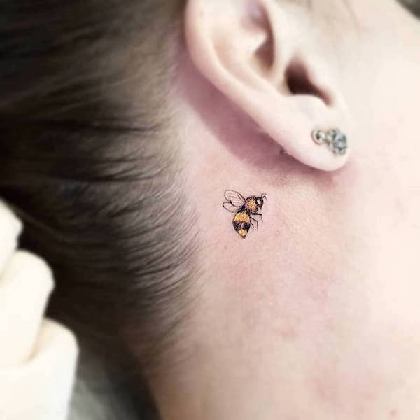 A tiny bee tattoo behind the ear by @karoldiastattooist