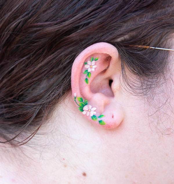 Colored small flowers and leaves ear tattoo by @heeyajenny