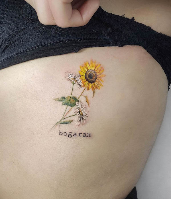 Daisy and sunflower rib tattoo by @karinart_tattoo