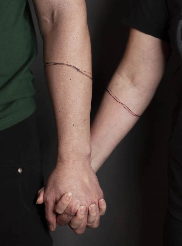 Matching single line bracelet tattoos by @meester_prikkebeen