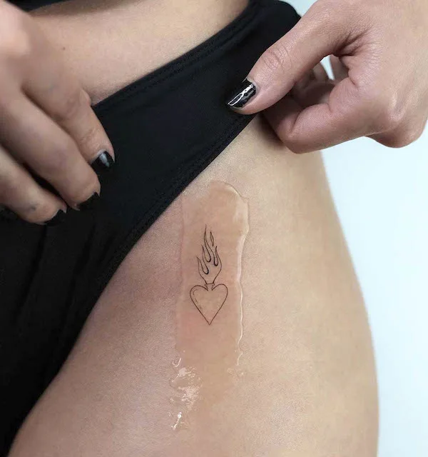 Small heart on fire hip tattoo by @akkurat_tattoo