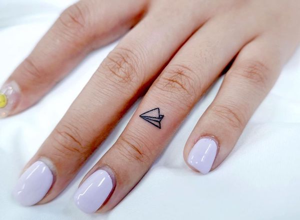 Small paper plane finger tattoo by @simbar_tattoo