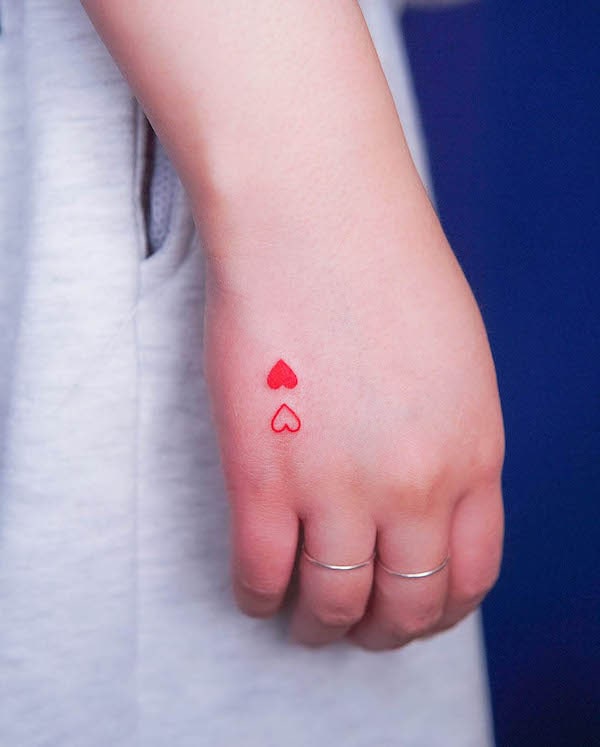 Small red hearts hand tattoo by @baam.kr