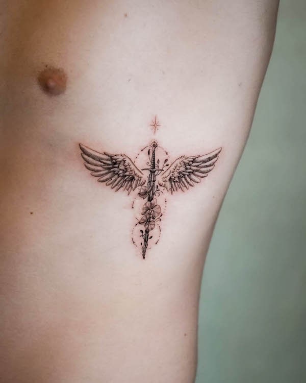 Small sword with wings rib tattoo by @tattooist_fini