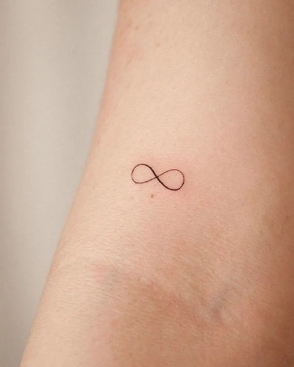 Tiny infinity arm tattoo by @orma_tattoo