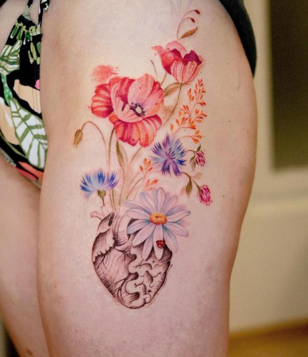 Cornflower poppy daisy growing from heart thigh tattoo